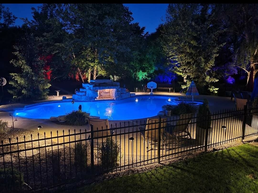 Garden path with professional landscape uplighting on trees and shrubs at night